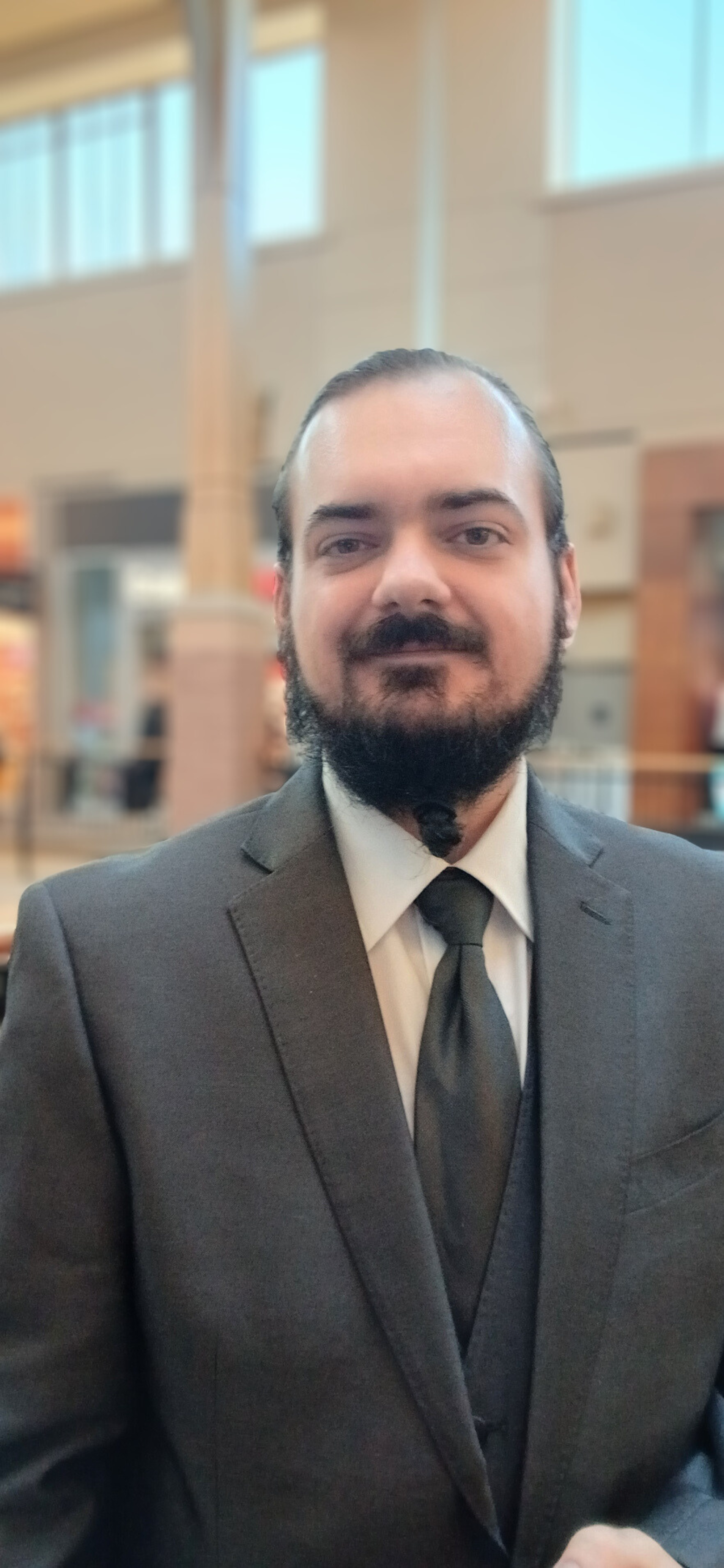 Photo of Troy wearing a grey suit.